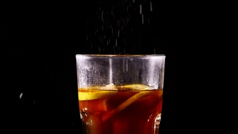 Small particles falling into glass of cocktail slowmo Stock Footage 84074205
