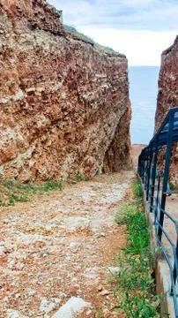 A small passage between steep cliffs. View of the beach between the high stone Stock Photos