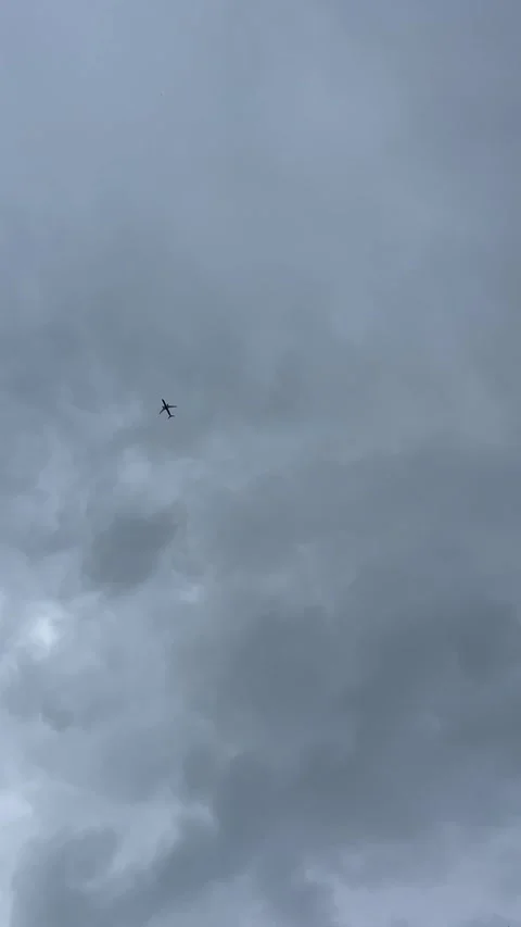 Small passenger airplane flying under heavy overcast clouds in vertical sky Видео 336547539