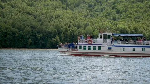 A small passenger ship floats on the background of forest mountains on the lake Stock Footage 122004952