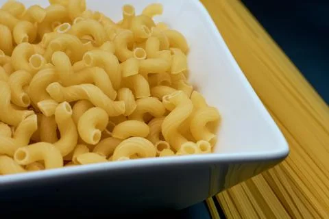 Small pasta in the shape of a spring in a white plate Spaghetti pasta on a da Stock Photos