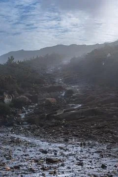 Small path of water runing down the rocks between the mist in a trail 写真素材