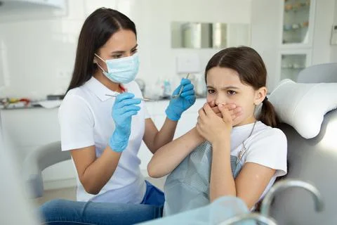 Small patient is afraid of dentist in modern dental clinic Stock Photos