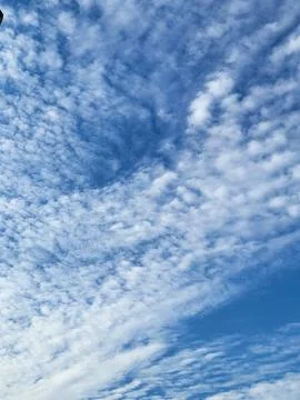 Small patterned cirrocumulus clouds covering bright blue sky Stock Photos