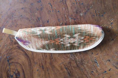 A small patterned fabric pouch with a zipper placed on a rustic wooden surf.. Stockfoto's