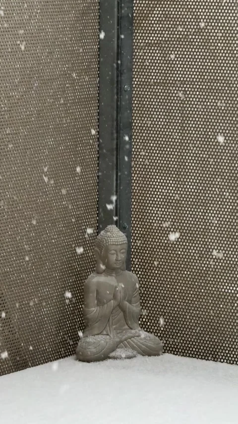 Small Peaceful Buddha statue sitting in a winter snowfall Stock Footage 346583224