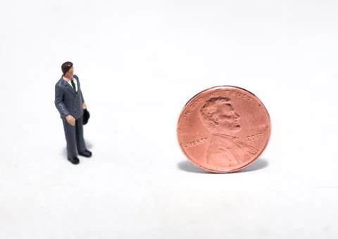 Small people looking at a penny Stock Photos