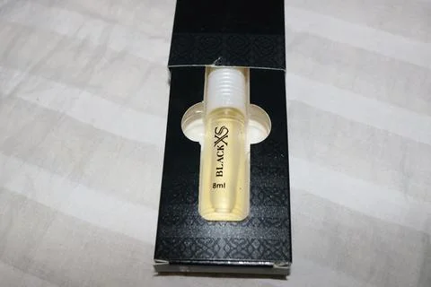 Small perfume bottle with white cap in black box on white surface 写真素材