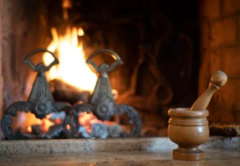 Small pestle and mortar in front of a burning fire Stock Photos