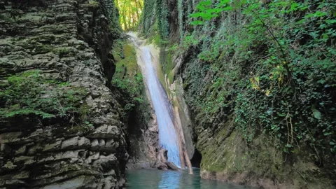 Small picturesque waterfall in summer forest. Water falls between cliffs with Video stock 224506907