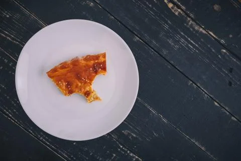 A small piece or bite of pie, leftover on white plate on black wooden table Stock-Fotos