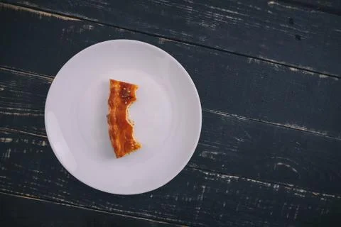 A small piece or bite of pie, leftover on white plate on black wooden table Stock Photos