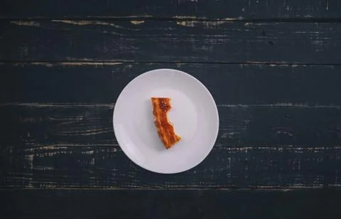 A small piece or bite of pie, leftover on white plate on black wooden table Stock Photos