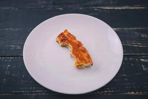 A small piece or bite of pie, leftover on white plate on black wooden table Stock Photos