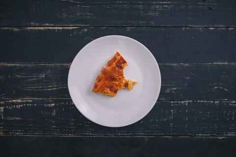 A small piece or bite of pie, leftover on white plate on black wooden table Stock Photos