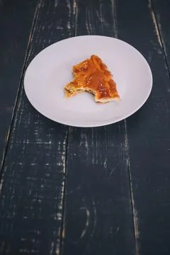 A small piece or bite of pie, leftover on white plate on black wooden table Stock Photos