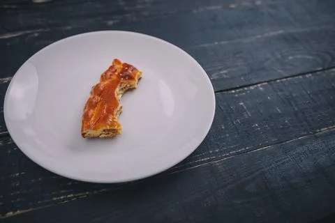 A small piece or bite of pie, leftover on white plate on black wooden table Stock Photos