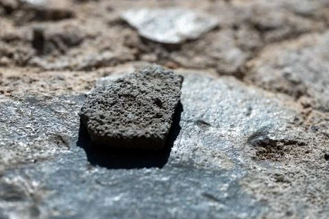 Small piece of rubble or concrete lying on a rough gray concrete surface Stockfoto's