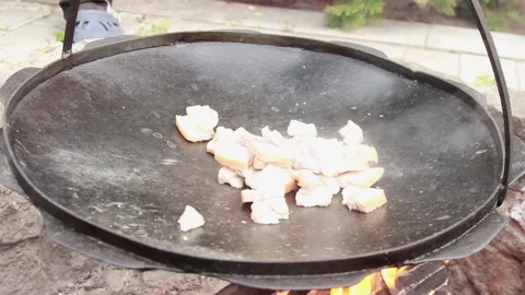 Small pieces of fat are fried in a large frying pan on coals Stock Footage 150046397