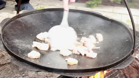 Small pieces of fat are fried in a large frying pan on coals Stock Footage 150046715
