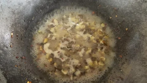 Small pieces of garlic and chilli flakes in hot olive oil in a cooking vessel Stock Footage 326475821