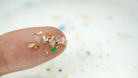 Small pieces of microplastic on the tip of a finger. 스톡 사진