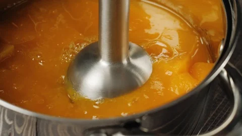 A small pieces of pumpkin is grinding by blender in a steel shiny saucepan. 4K Stock Footage 126419558