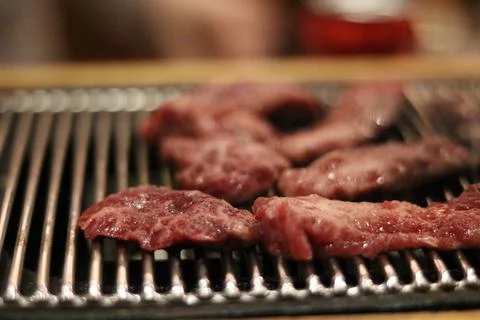 Small pieces of red raw beef cooking on metal barbecue Stock Photos
