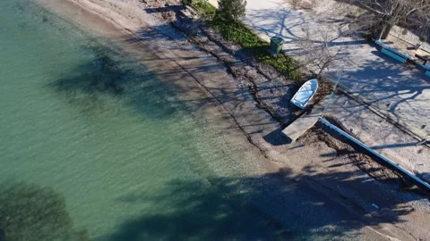 Small pier and white boat on quiet sandy beach with turquoise water Видео 343994564