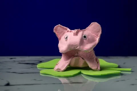 Small pig sitting on a cloverleaf made by a child Stock Photos