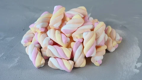Small pile of colourful marshmallows lie on grey background Stock Footage 128985654