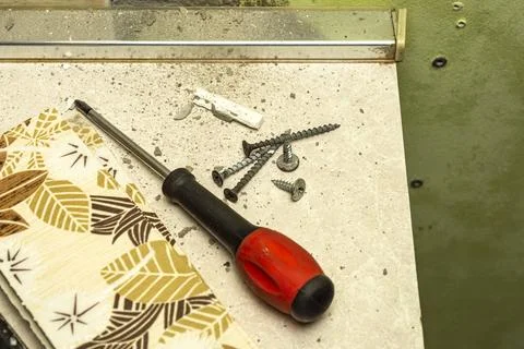 A small pile of self-tapping screws and a screwdriver, as well as some cera.. Stock Photos