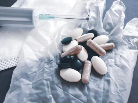 A small pile of various tablets and capsules lies on a disposable glove Stock Photos