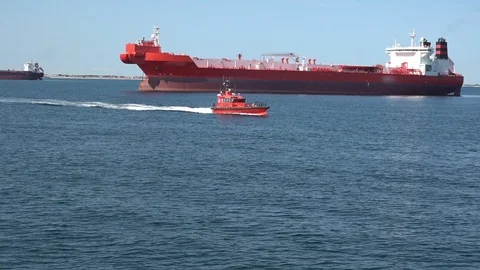 Small pilot motor ship sails fast against large red tanker Stock Footage 118356869
