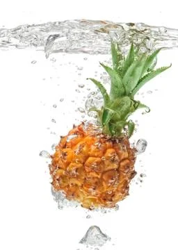 Small pineapple falling in water on white Stock Photos