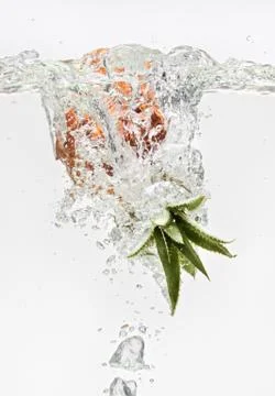 Small pineapple falling in water on white Foto stock