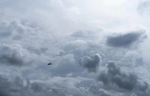 Small plane in cloudy sky for rainmaking. White fluffy clouds with small airc 库存照片