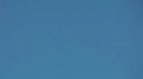 The small plane flies highly in the blue sky being lost in sun beams Stock Footage 23266304