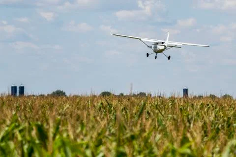 A small plane flies low over a farm field, Manitoba, Canada Stock Photos