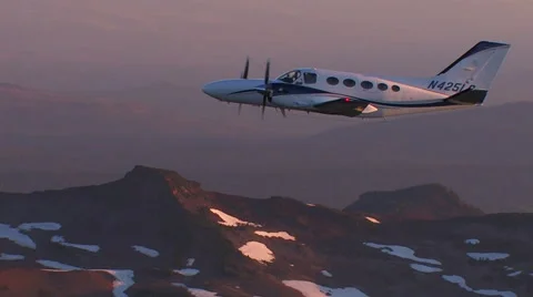 SMALL PLANE FLYING OVER MOUNTAINS AT SUNRISE Stock Footage 52557314