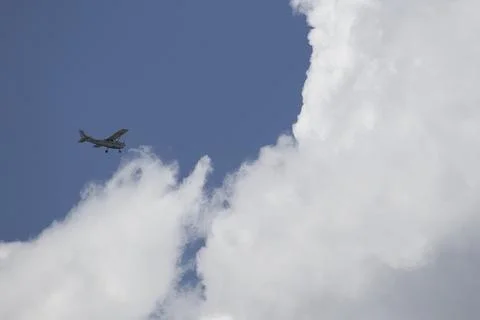 A small plane is flying through a cloudy sky Stock Photos