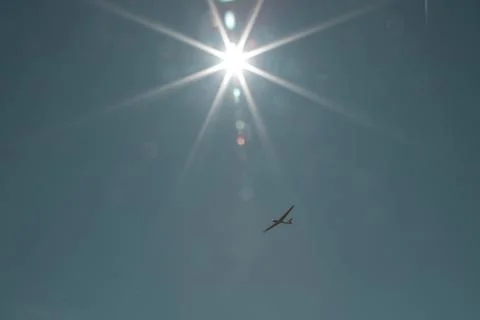 Small plane flying under the sun Stock Photos