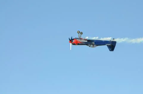A small plane with a propeller flying upside down Stock Photos