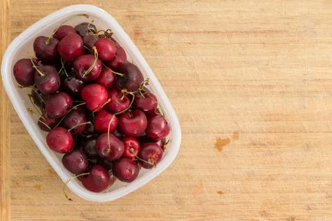 Small plastic container filled with red cherries Stock Photos