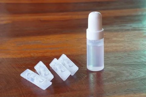 Small plastic dropper bottle with single-use liquid vials on wooden table. Conce Stock Photos