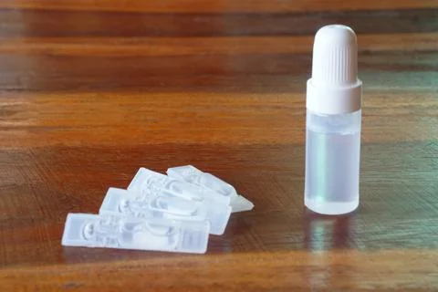 Small plastic dropper bottle with single-use liquid vials on wooden table. Conce Stock Photos