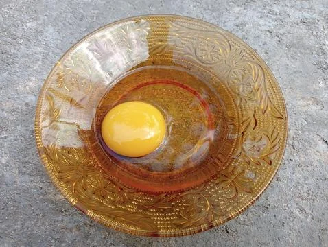 Small plate with raw egg on the cast wall. Foto stock
