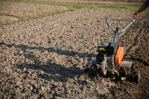 Small plowing machine in hands of a farmer making arable in black soil Stock Photos