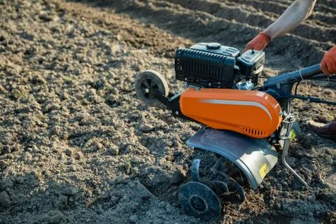 Small plowing machine in hands of a farmer making arable in black soil Stock Photos