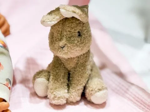 Small plush rabbit toy sitting on soft fabric. Childhood innocence, comfort.. Stock Photos